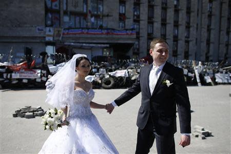 A newly married couple stands near a barricade outside a regional government building in Donetsk, in eastern Ukraine April 25, 2014. REUTERS/Marko Djurica