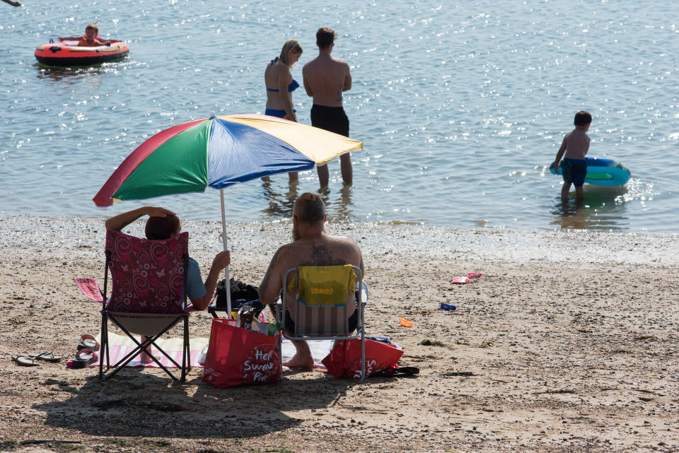 SOUTHEND-ON-SEA, ENGLAND - SEPTEMBER 14: Two people sit on deck chairs on the beach as people walk out into the sea on September 14, 2020 in Southend on Sea, England. Parts of the UK are expected to hit 29 degrees celsius as the country experiences a late-summer Heatwave.  (Photo by John Keeble/Getty Images)