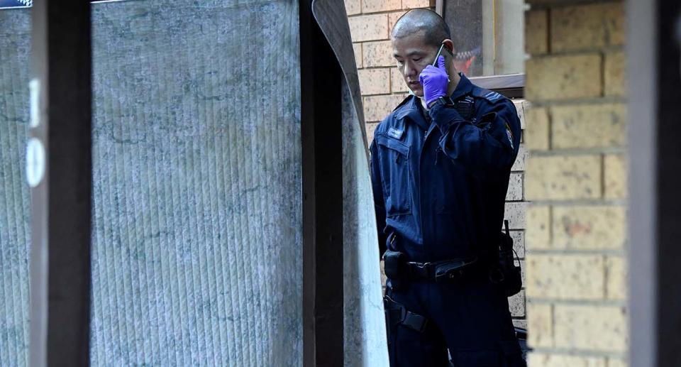 A NSW Police officer talks on the phone during a raid on a home in Greenacre, Sydney in connection to three men charged with terrorism offences.