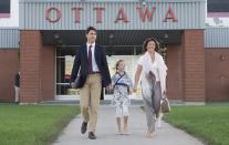 <p>Right before jetting off for the PM’s first official visit to China, the Trudeaus boarded a private plane in style: Sophie opted for an easy pair of silky pants and a white T-shirt combined with a pretty watercolour scarf and carryall bag. Her husband Justin kept things simple in a navy blazer, while their adorable daughter Ella-Grace rocked a kimono-style dress.<i> (Photo by Adrian Wyld/The Canadian Press via AP)</i></p>