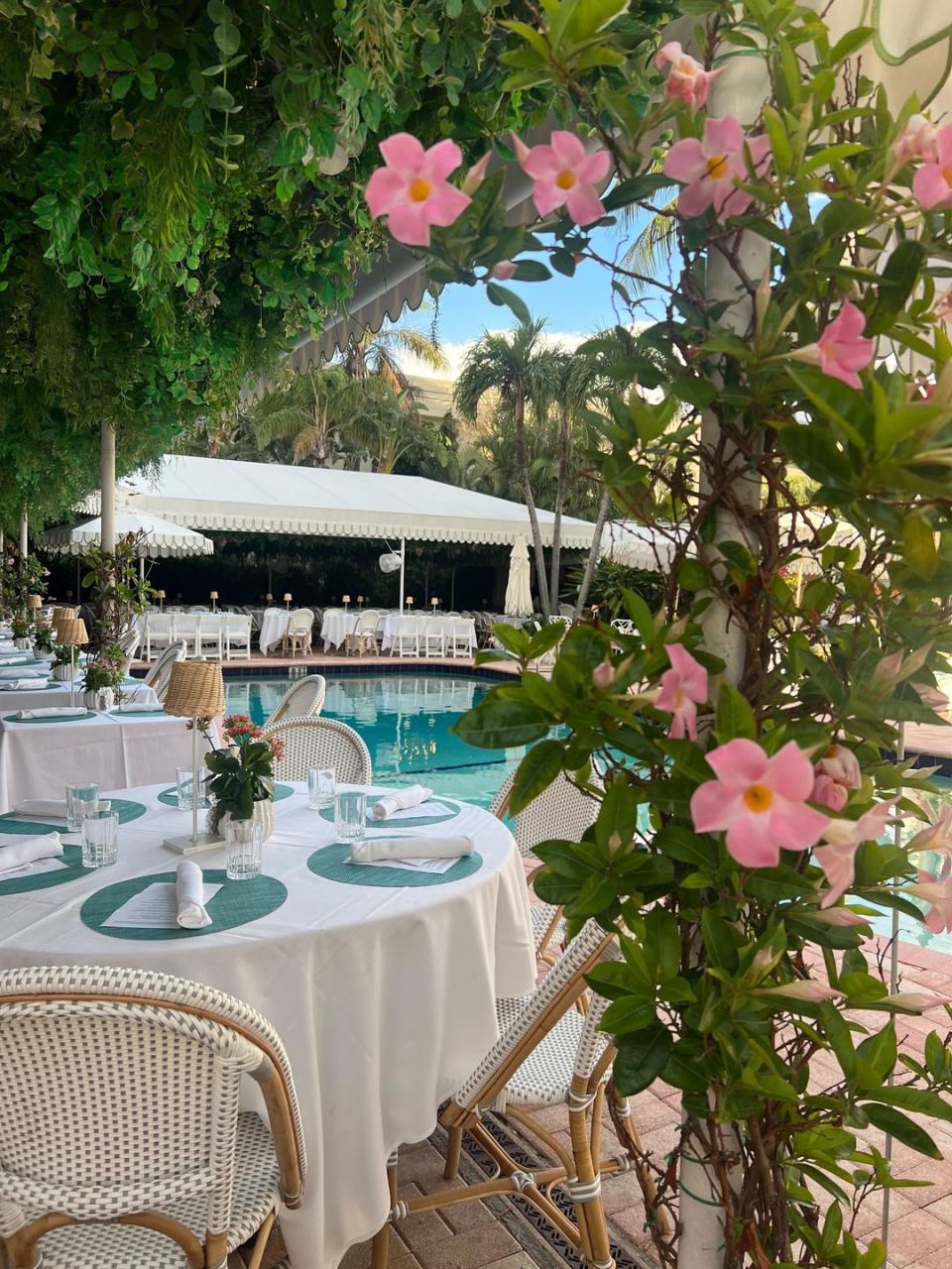 a table with flowers and chairs by the pool