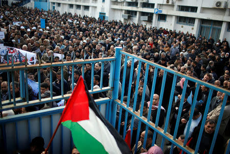 An employee of United Nations Relief and Works Agency (UNRWA) holds a Palestinian flag during a protest against a U.S. decision to cut aid, in Gaza City January 29, 2018. REUTERS/Mohammed Salem