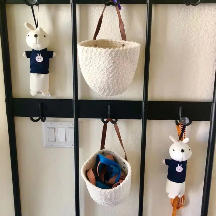 Same reviewer's photo of the white baskets with brown handles, now seen hanging on a metal hall tree frame