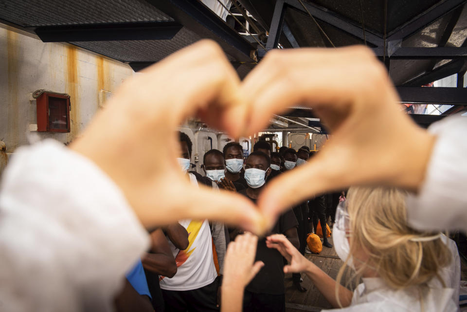 Volunteers salute some of the 353 migrants rescued by Sea-Watch 4 as they prepare to board the quarantine Ferry Gnv Allegra, in front of the port of Palermo, Italy, Wednesday, Sept. 2, 2020. (Chris Grodotzki/Sea-Watch.org via AP)