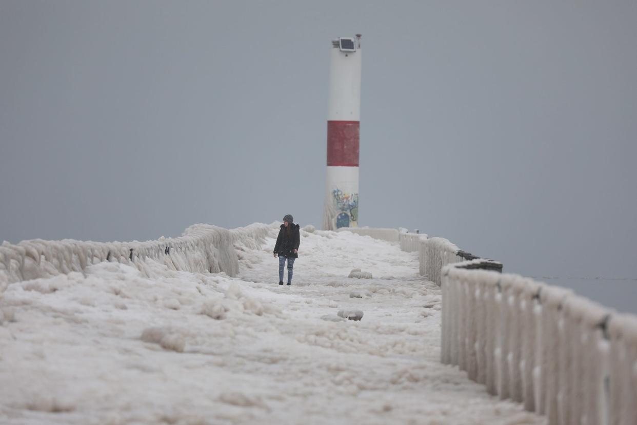Amanda McDaniels of Rochester makes her way slowly back from the end of an ice-covered Charlotte Pier on Thursday.