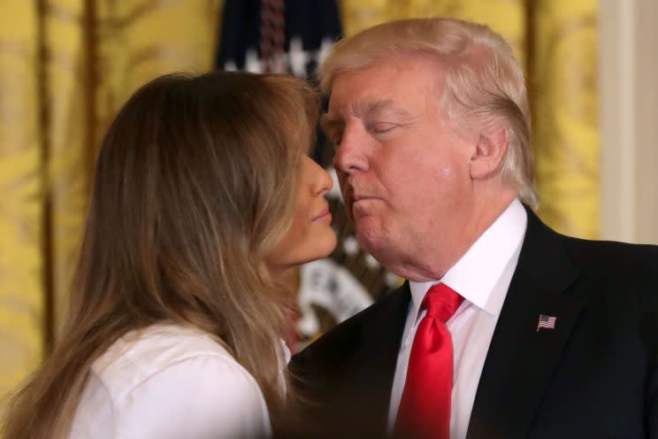 First lady Melania Trump and President Trump share a kiss at the White House on Friday