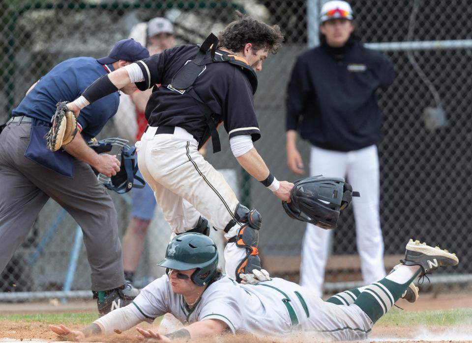 Central Catholic's Jordan Puperi steals home safely in the sixth inning under the late tag of Aquinas catcher Owen Burick at Aquinas Thursday, April 20, 2023. 