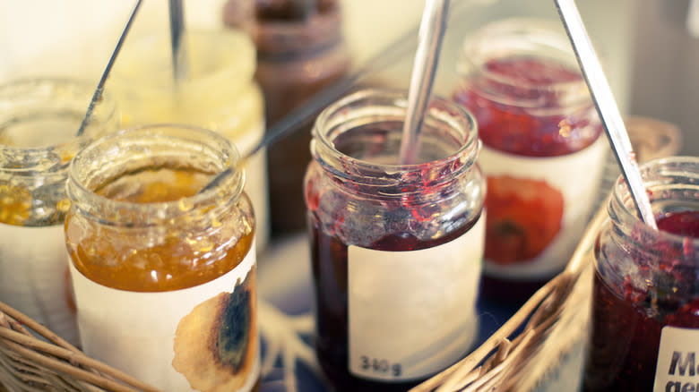 Several jars of fruit jam with spoons in them