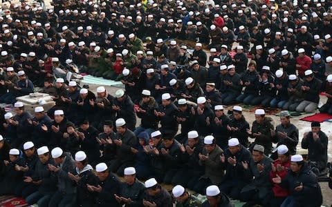 Muslims pray outside a mosque during Eid al-Adha celebrations in Wuzhong - Credit: Corbis News/ Jie Zhao