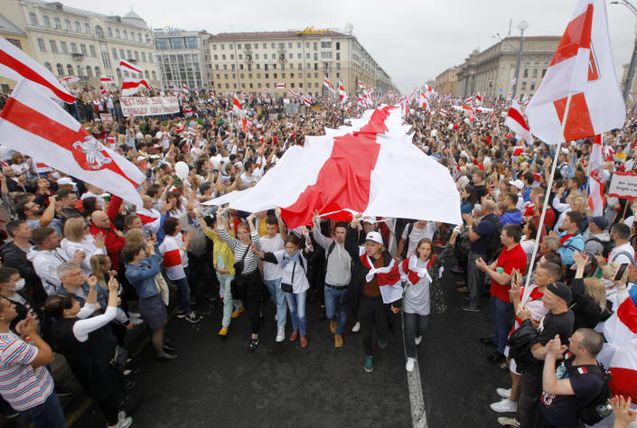 Demonstrators carry a huge historical flag of Belarus as thousands gather for a protest at the Independence square in Minsk, Belarus, Sunday, Aug. 23, 2020. Demonstrators are taking to the streets of the Belarusian capital and other cities, keeping up their push for the resignation of the nation&#39;s authoritarian leader. President Alexander Lukashenko has extended his 26-year rule in a vote the opposition saw as rigged. (AP Photo/Dmitri Lovetsky)