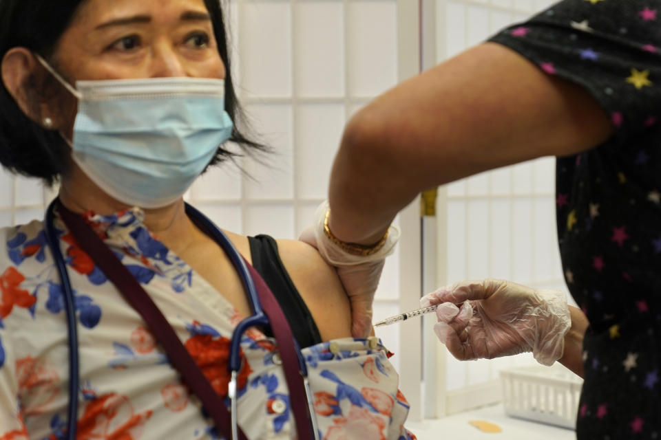 FILE - Cristina Licup receives her COVID-19 booster shot where she works at the Hebrew Home at Riverdale in New York, Monday, Sept. 27, 2021.   A requirement to get vaccinated against COVID-19 kicks in Thursday, Jan. 27, 2022 for millions of health care workers in about half the states. (AP Photo/Seth Wenig, File)