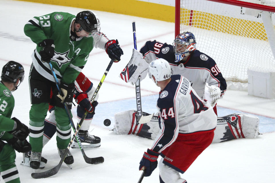 Dallas Stars defenseman Esa Lindell (23) tries to score on Columbus Blue Jackets goaltender Elvis Merzlikins (90) during the first period of an NHL hockey game Thursday, April 15, 2021, in Dallas. (AP Photo/Richard W. Rodriguez)