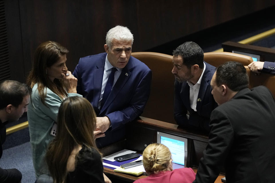 Israeli opposition leader Yair Lapid, center, confers with colleagues during a vote on picking two lawmakers to serve on a judge selection panel, in the Knesset, Israel's parliament, Jerusalem, Wednesday, June 14, 2023. (AP Photo/Ohad Zwigenberg)