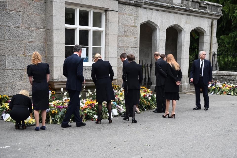 From left, Britain's Sophie, Countess of Wessex, Britain's Lady Louise Windsor, Vice Admiral Timothy Laurence, Zara Phillips, Peter Phillips, Britain's Princess Anne, Princess Royal, Britain's Prince Edward, Earl of Wessex, Britain's Princess Eugenie of York, Britain's Princess Beatrice of York and Britain's Prince Andrew, Duke of York, look at the flowers placed outside Balmoral Castle in Ballater, on September 10, 2022, two days after Queen Elizabeth II died at the age of 96. - King Charles III pledged to follow his mother's example of 