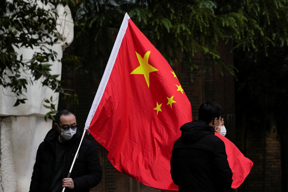 People wearing face masks pose for photos with a Chinese national flag at a park, as coronavirus disease (COVID-19) outbreaks continue in Shanghai, China, December 12, 2022. REUTERS/Aly Song