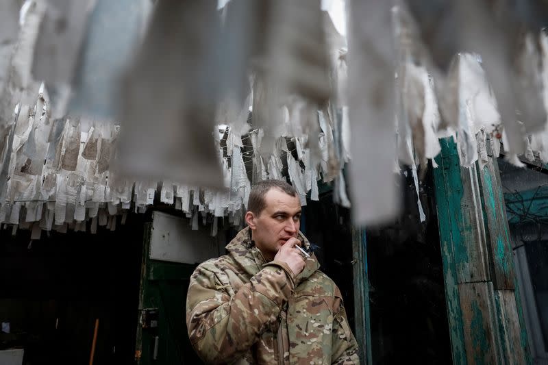 Ukrainian serviceman smokes under camouflage nets in Donetsk region