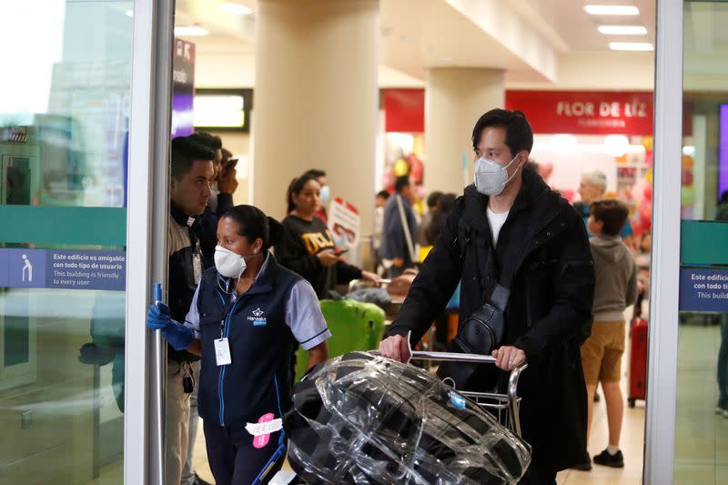 People wear surgical masks at the Mariscal Sucre International Airport, after the first case of a fast-spreading new coronavirus was confirmed in the country, in Quito