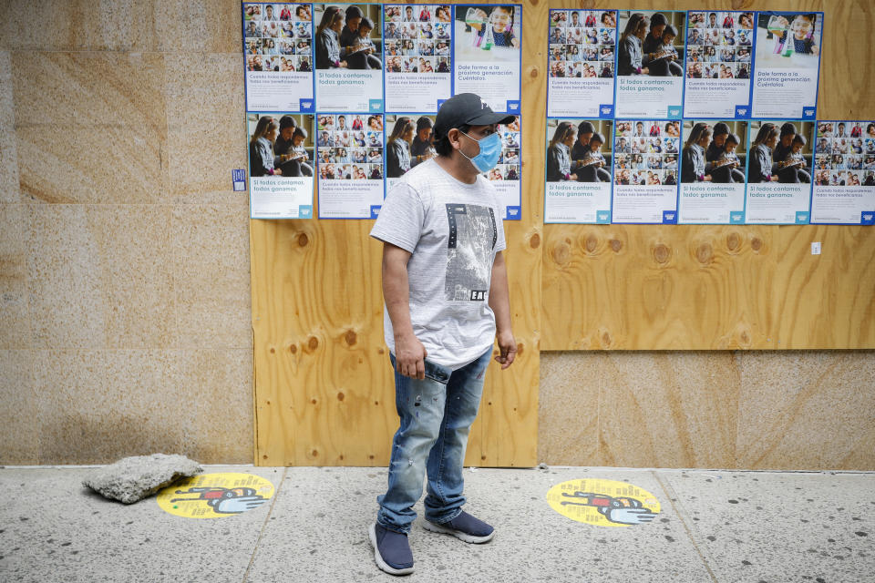 A pedestrian wearing a protective mask waits on line for food donations, while maintaining social distancing, during the COVID-19 pandemic Tuesday, June 23, 2020, in the Corona neighborhood of the Queens borough of New York. (AP Photo/John Minchillo)