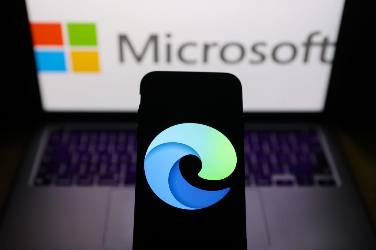 Microsoft Edge logo on a phone with Microsoft's logo behind it