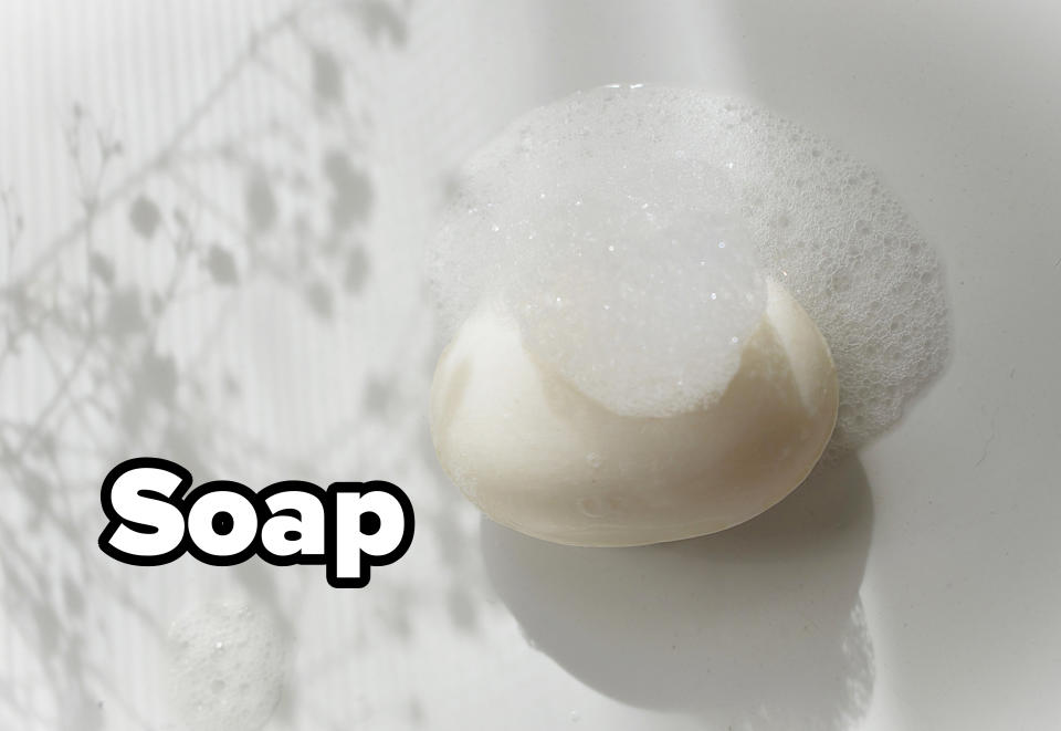 A bar of soap with foam on top, placed on a white surface with soft shadows in the background