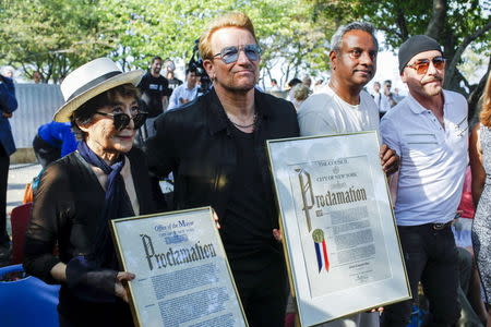 Artist Yoko Ono, (L) the widow of John Lennon, poses with Bono (C-L) and guitarist The Edge of U2 (R) during the unveiling of a tapestry honoring Lennon at Ellis Island in New York July 29, 2015. REUTERS/Eduardo Munoz
