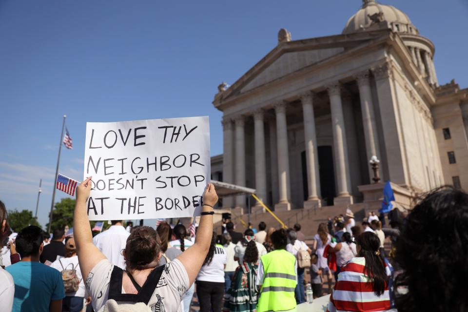 A person holds a "Love Thy Neighbor" sign during a demonstration in support of the immigrant community before Hispanic Cultural Day Wednesday at the state Capitol.