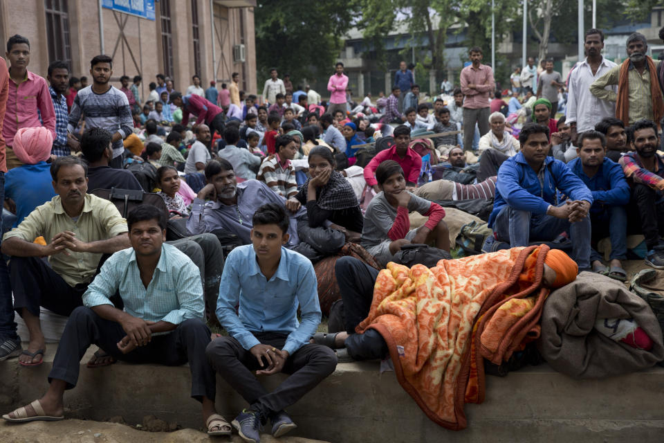 In this Tuesday, Aug. 6, 2019 photo, Indian migrant workers wait outside the government transport yard waiting to buy bus tickets to leave the region, during curfew in Srinagar, Indian controlled Kashmir. Hit by a complete security lockdown in Kashmir, hundreds of poor migrant workers have begun fleeing the Himalayan region to return to their far-away villages in northern and eastern India. (AP Photo/ Dar Yasin)