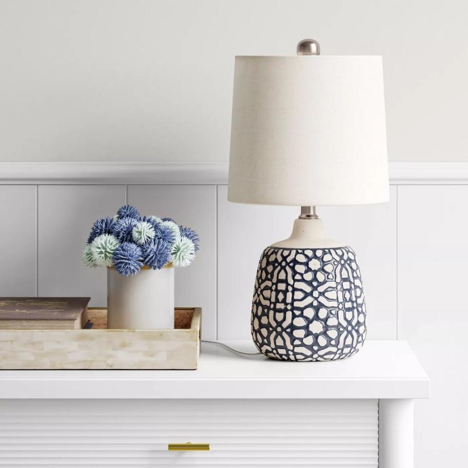 The lamp with a white shade and an intricate white and blue base on a table