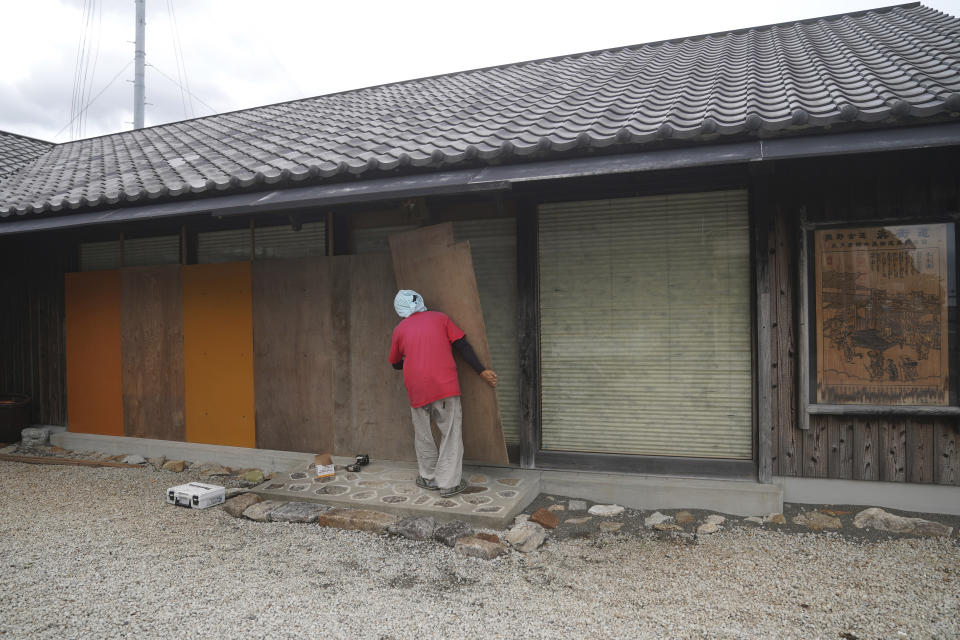 A man places wood boards to protect glasses from Typhoon Hagibis at a shop in Kumano, Mie Prefecture, Japan Friday, Oct. 11, 2019. A powerful typhoon was forecast to bring 2 feet of rain and damaging winds to the Tokyo area this weekend, and Japan's government warned people Friday to stockpile supplies and evacuate before it's too dangerous. (AP Photo/Toru Hanai)