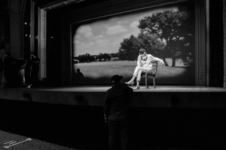 A woman seated on a chair onstage.