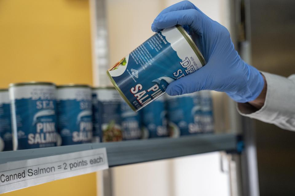 A volunteer at Bread for the City, selects a can of salmon for a patron, Wednesday, May 10, 2023, at the food pantry in Washington. The formal end of the national Public Health Emergency on Thursday marks the end of several U.S. pandemic-era emergency support program, from extra food assistance to automatic enrollment in Medicaid. (AP Photo/Jacquelyn Martin)