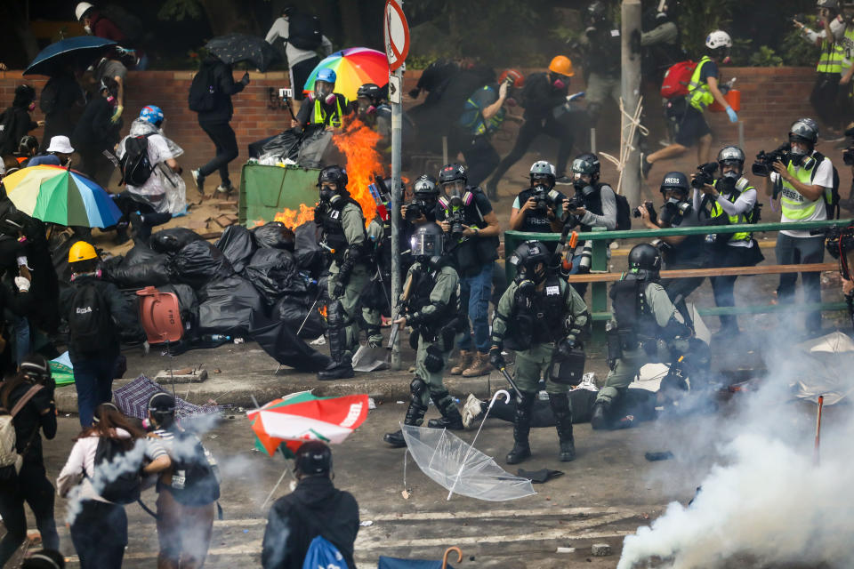 Protesters (L) run back to the campus after police advanced while they were trying to leave Hong Kong Polytechnic University in Hung Hom district of Hong Kong on November 18, 2019. - Pro-democracy demonstrators holed up in a Hong Kong university campus set the main entrance ablaze November 18 to prevent surrounding police moving in, after officers warned they may use live rounds if confronted by deadly weapons. (Photo by DALE DE LA REY / AFP) (Photo by DALE DE LA REY/AFP via Getty Images)