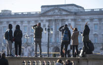 Tourists take photos outside the gates of Buckingham Palace, following a statement by Britain's Queen Elizabeth II and Buckingham Palace, in London, Sunday, Jan, 19, 2020. Buckingham Palace says Prince Harry and his wife, Meghan, will no longer use the titles "royal highness" or receive public funds for their work under a deal that allows them to step aside as senior royals. (Dominic Lipinski/PA via AP)