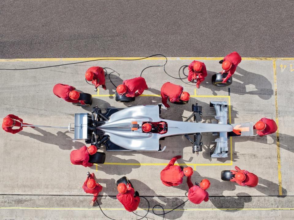 A racing crew servicing a race car in the pit lane.