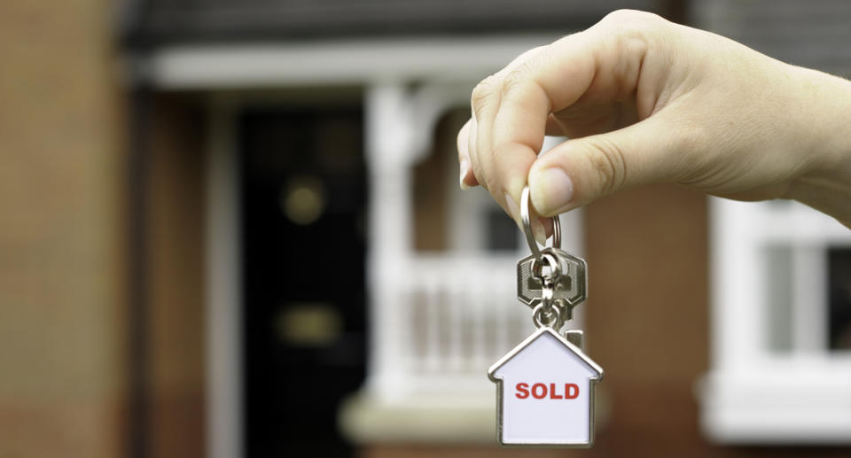 A female holding the house keys to property she just purchased.