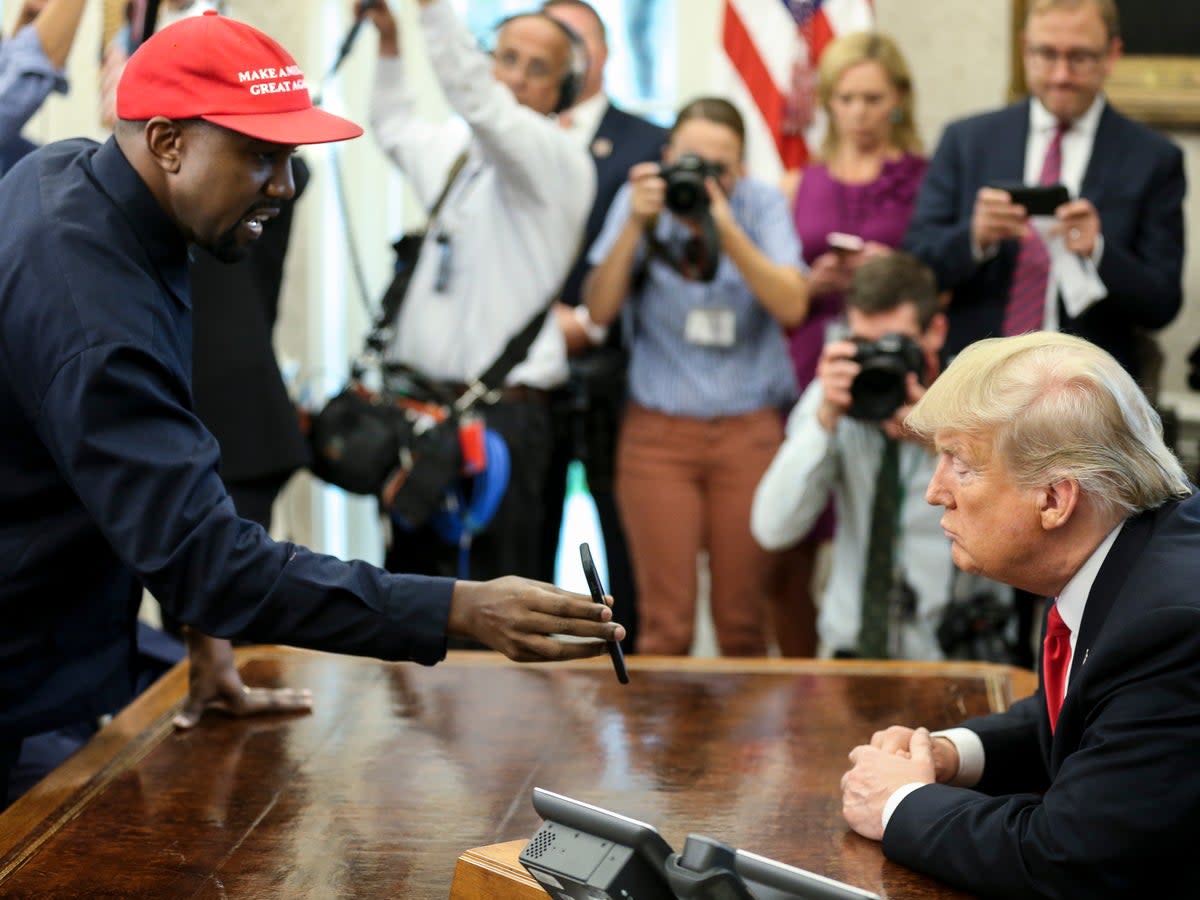 Kanye West muestra una foto en un teléfono a Donald Trump durante una reunión en la oficina Oval (Getty Images)