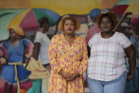 Krystina Francois, left, and Francesca Menes, children of Haitian immigrants to the U.S. and co-founders of the Black Collective, pose for a picture in front of a mural at the Little Haiti Cultural Center, Tuesday, Sept. 21, 2021, in Miami. Menes and Francois, whose advocacy organization focuses on the political needs and economic empowerment of Black people across the African diaspora, have called for the Biden administration to immediately suspend plans to remove migrants via planes bound for Haiti. (AP Photo/Rebecca Blackwell)