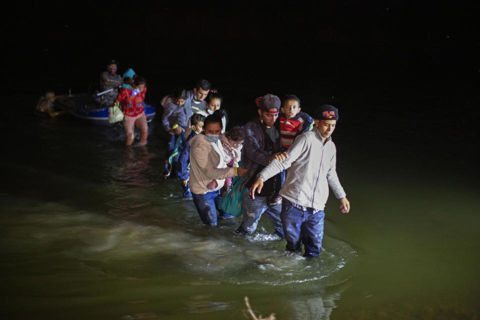 Migrant families, mostly from Central American countries, wade through shallow waters after being delivered by smugglers on small inflatable rafts on U.S. soil in Roma, Texas, Wednesday, March 24, 2021. As soon as the sun sets, at least 100 migrants crossed through the Rio Grande river by smugglers into the United States. (AP Photo/Dario Lopez-Mills)