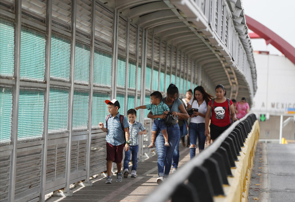 FILE - In this June 28, 2019 file photo, local residents with visas walk across the Puerta Mexico international bridge to enter the U.S., in Matamoros, Tamaulipas state, Mexico. A U.S. judge in Oregon on Tuesday, Nov. 26, 2019, granted a preliminary injunction blocking a Trump administration proclamation that would require immigrants to show proof of health insurance to get a visa. (AP Photo/Rebecca Blackwell, File)