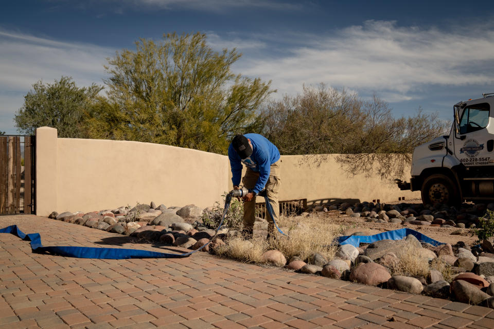 Un transportista de agua coloca mangueras para llenar el tanque en una casa que está a la venta en Rio Verde Foothills, en las afueras de Scottsdale, Arizona, el domingo 8 de enero de 2023. (Erin Schaff/The New York Times).