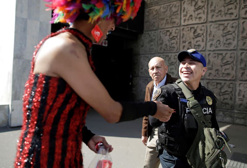 Polo Gomez, also known as drag queen Yolanda la del Rio, from organization Condomovil A.C., gives out a free condom to a police officer during an event organized by AIDS Healthcare Foundation for the International Condom Day, in Mexico City