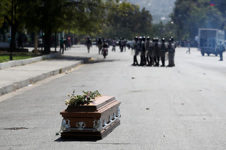 The casket of a man shot dead during anti-government protests lies on the ground as riot police release tear gas to disperse locals residents in Port-au-Prince, Haiti, February 22, 2019. REUTERS/Ivan Alvarado