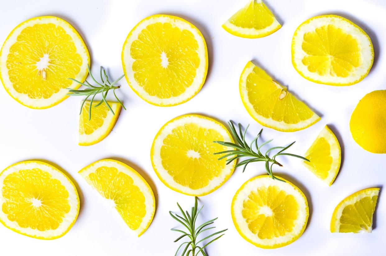 Slices of lemon and sprigs of rosemary scattered on a white background