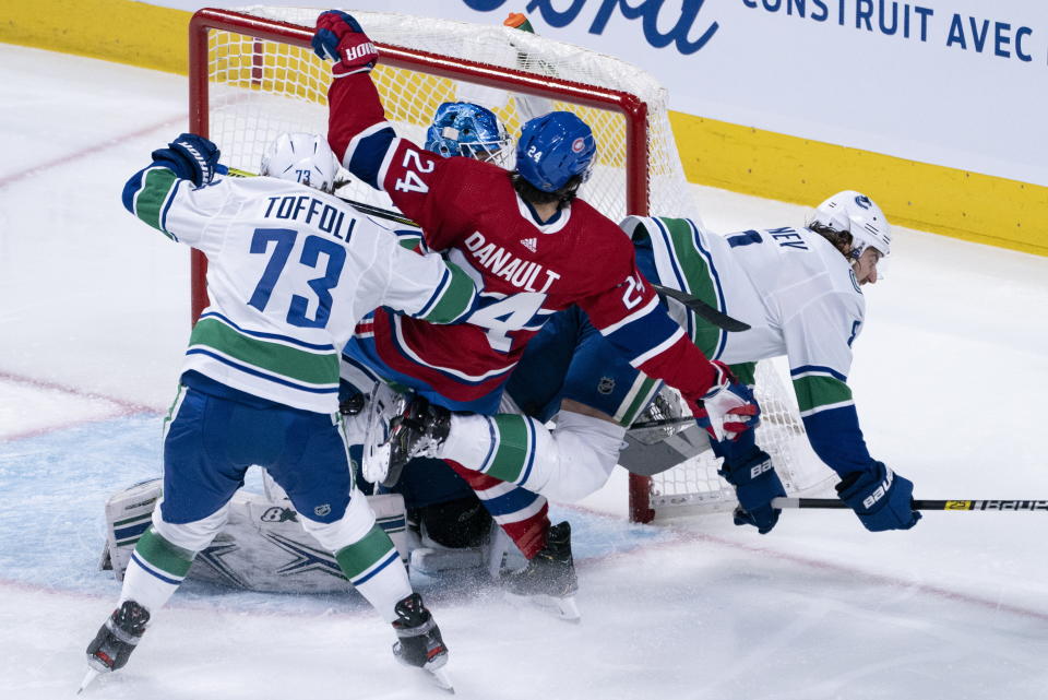 Montreal Canadiens' Phillip Danault gets tangled up between Vancouver Canucks' Tyler Toffoli, left, and Christopher Tanev in front of goaltender Thatcher Demko during the second period of an NHL hockey game Tuesday, Feb. 25, 2020, in Montreal. (Paul Chiasson/The Canadian Press via AP)