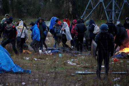 French riot police watch Iranian Kurdish migrants, during the dismantling of a camp in Calais, France, January 10, 2019. Picture taken January 10, 2019. REUTERS/Pascal Rossignol