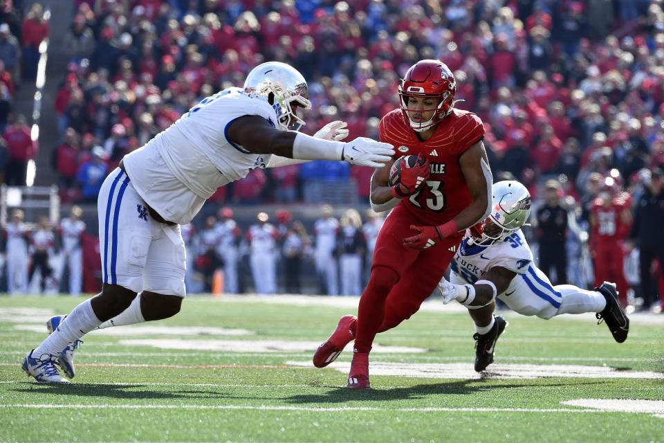 Louisville running back Isaac Guerendo (23) is tackles by Kentucky linebacker Trevin Wallace (32), and defensive lineman Deone Walker (0) during the second half of an NCAA college football game in Louisville, Ky., Saturday, Nov. 25, 2023. Kentucky won 38-31. (AP Photo/Timothy D. Easley)
