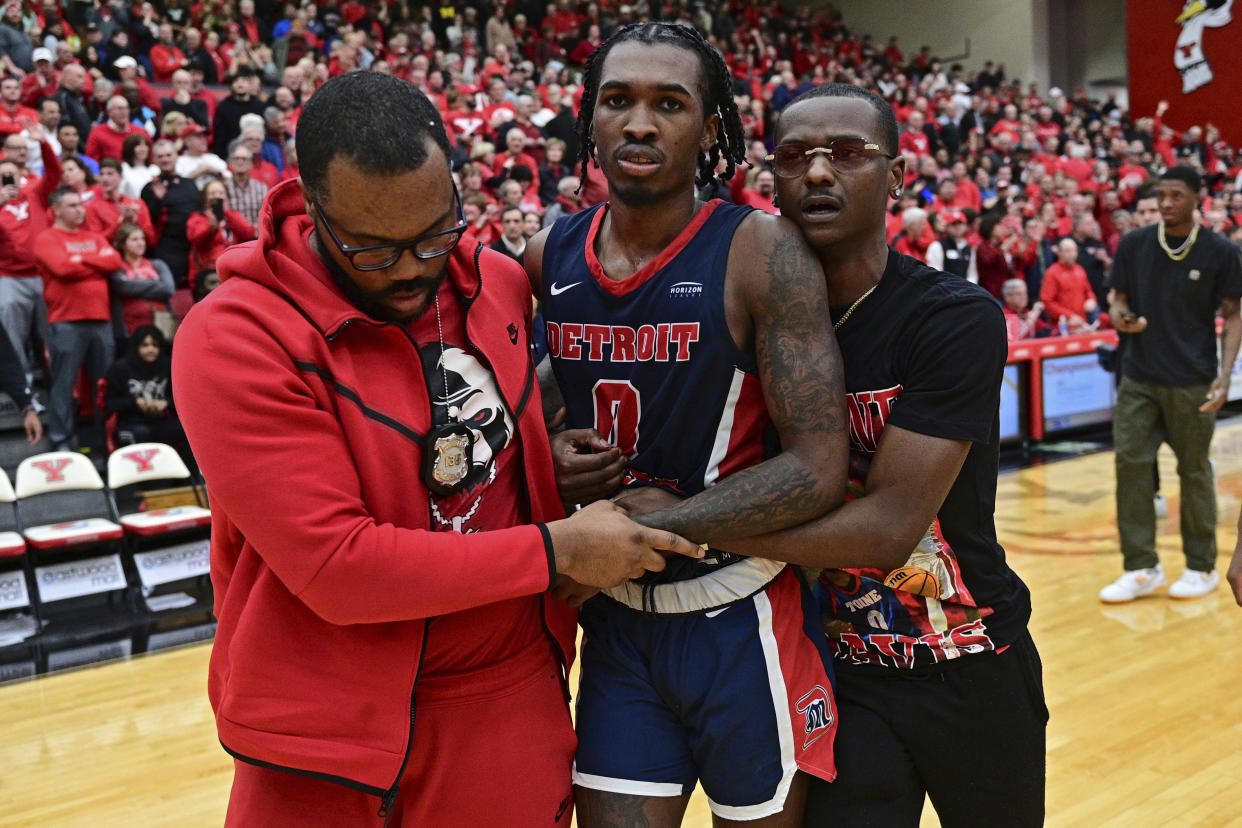 Detroit Mercy guard Antoine Davis, center, is assisted off the floor by bodyguard Daniel Toomer, left, and manager Nathan Harrison, right, after his team was defeated by Youngstown State in an NCAA college basketball game in the quarterfinals of the Horizon League tournament, Thursday, March 2, 2023, in Youngstown, Ohio.(AP Photo/David Dermer)