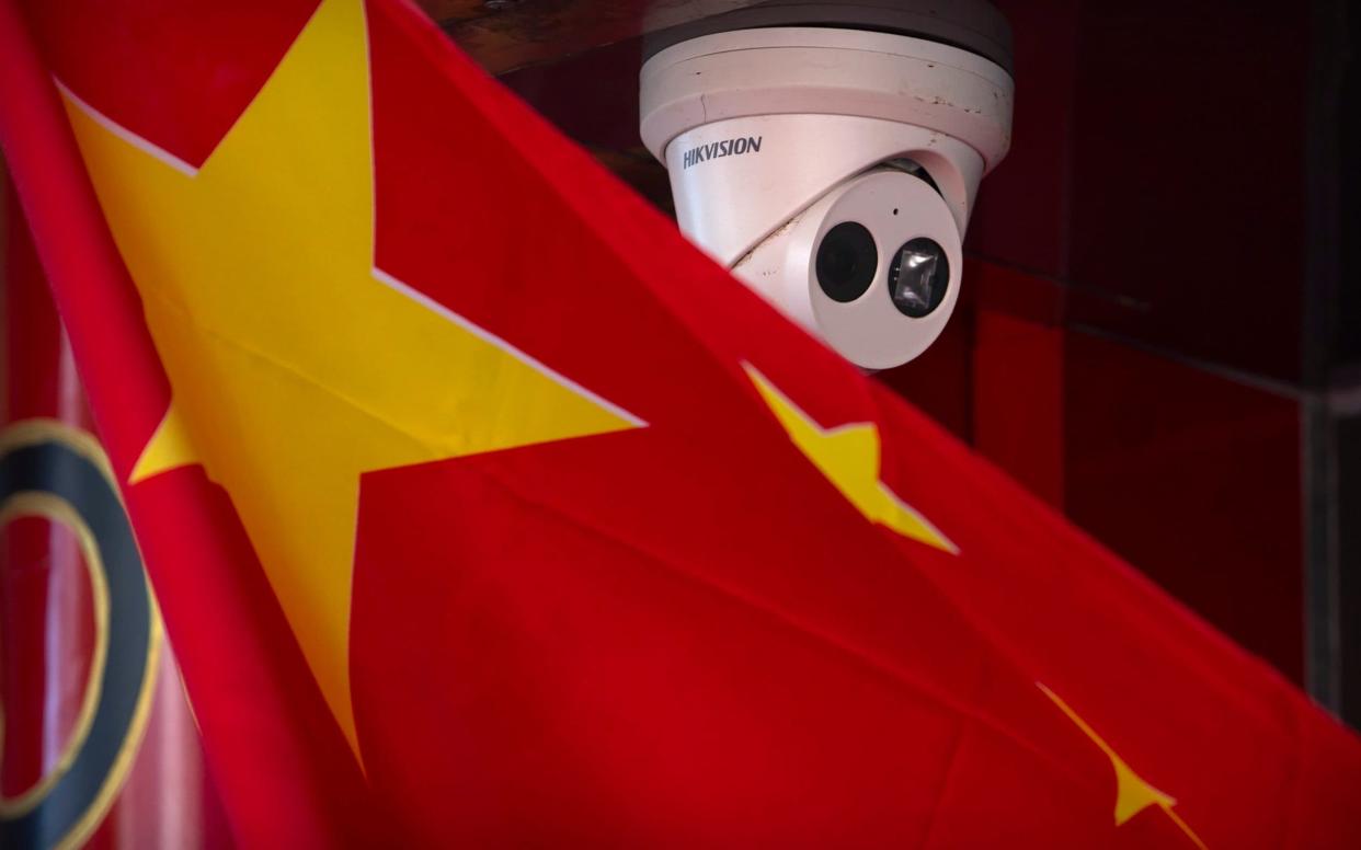 A Chinese flag hangs near a Hikvision security camera outside of a shop in Beijing - AP