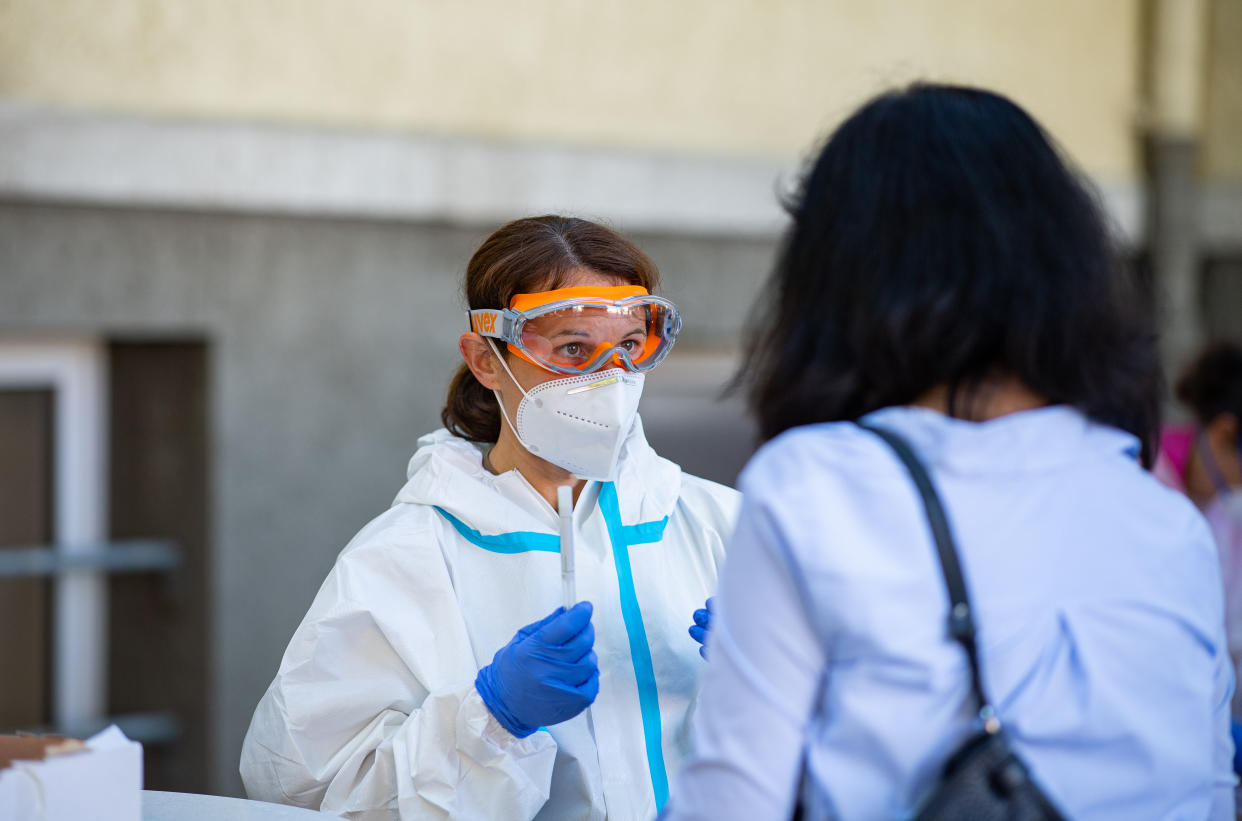 25 June 2020, North Rhine-Westphalia, Oelde: A member of the Bundeswehr takes a smear test on a woman at a corona smear site in Oelde. Because of the corona outbreak at the meat producer Tönnies in Rheda-Wiedenbrück, many people from the area cannot easily escape on holiday: In several popular regions at home and abroad, negative tests are being demanded of them. Photo: Guido Kirchner/dpa (Photo by Guido Kirchner/picture alliance via Getty Images)