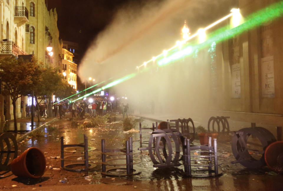 Anti-government protesters use their Laser ray lights, as they are sprayed by water from the riot police during a protest near the parliament square, in downtown Beirut, Lebanon, Sunday, Dec. 15, 2019. Lebanese security forces fired tear gas, rubber bullets and water cannons Sunday to disperse hundreds of protesters for a second straight day, ending what started as a peaceful rally in defiance of the toughest crackdown on anti-government demonstrations in two months. (AP Photo/Hussein Malla)